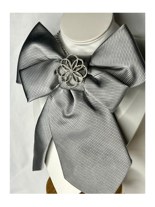 sidovy och närbild av slipsrosett i silvergrå ton med en dekorativ blomliknande detalj