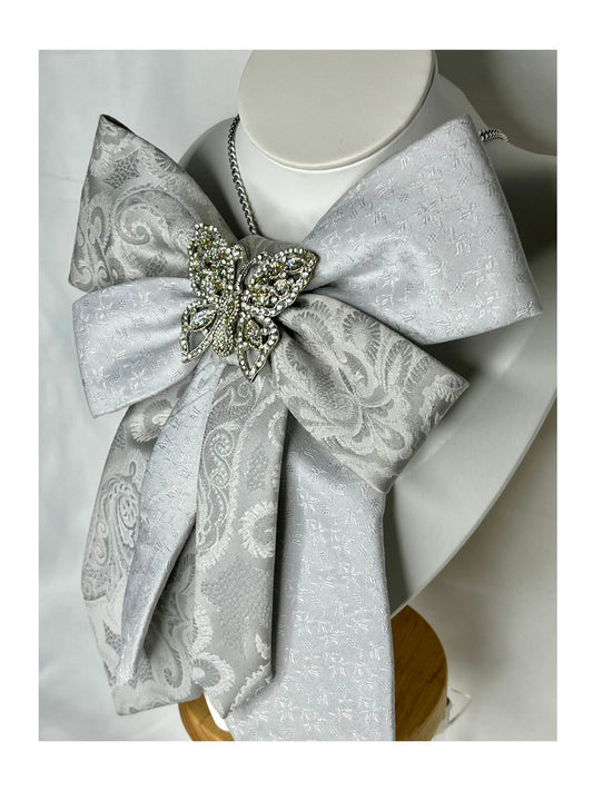 Sidovy och närbild av handgjord slipsrosett i skimrande silver med detaljrika mönster 