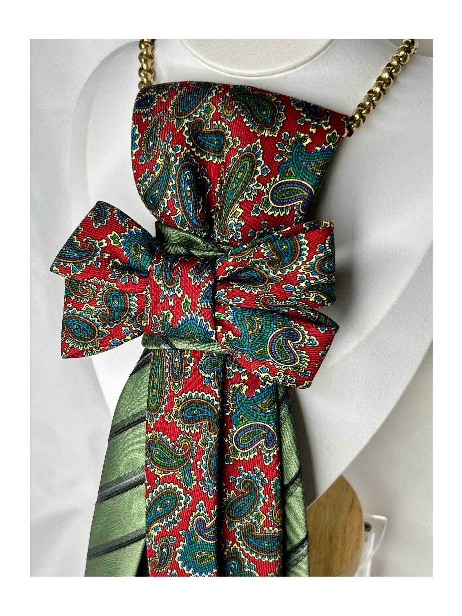 Närbild av handgjord slipsrosett i klassiska rödgröna toner med paisleymönster