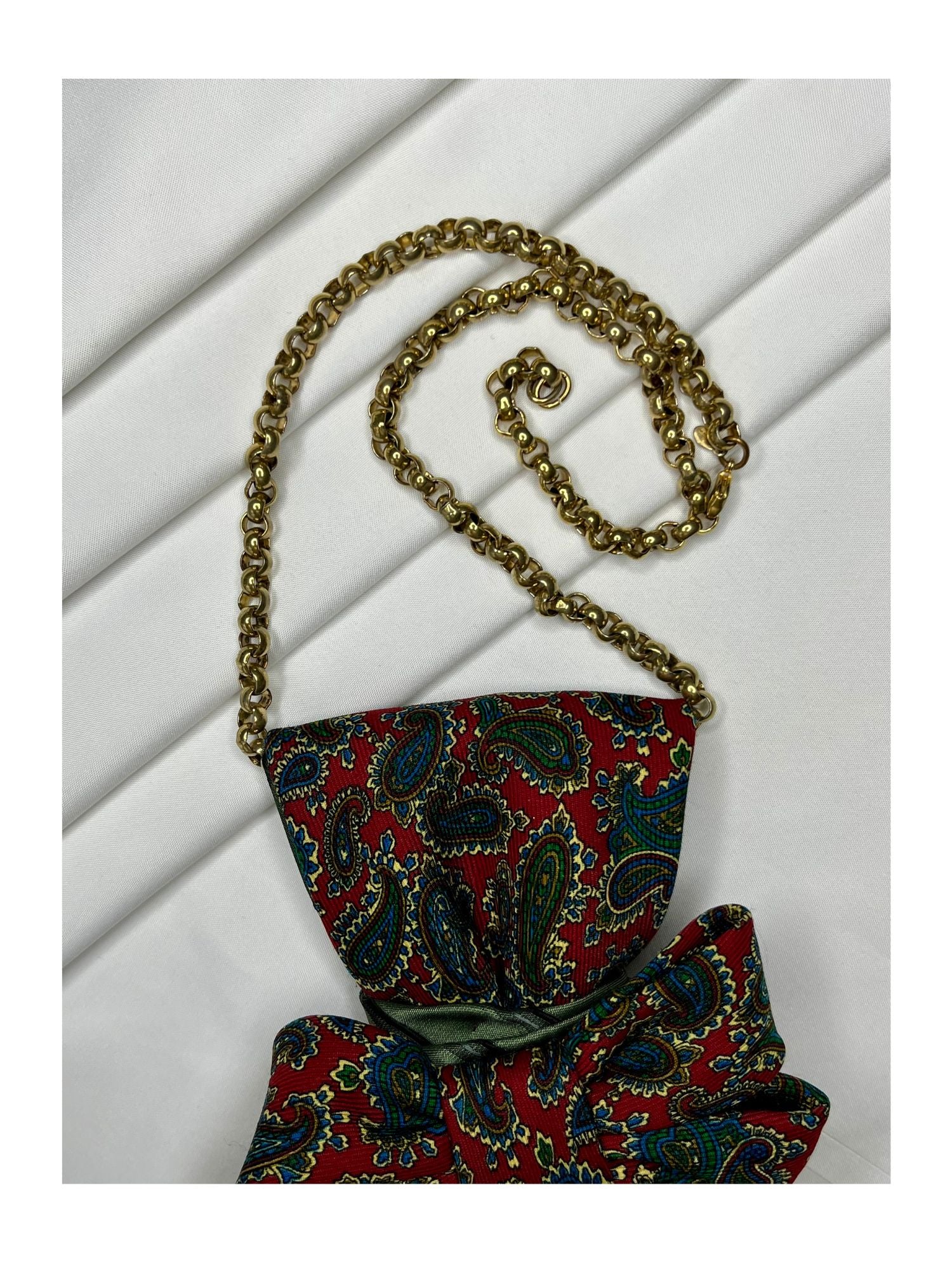 Närbild av halskedja för handgjord slipsrosett i klassiska rödgröna toner med paisleymönster