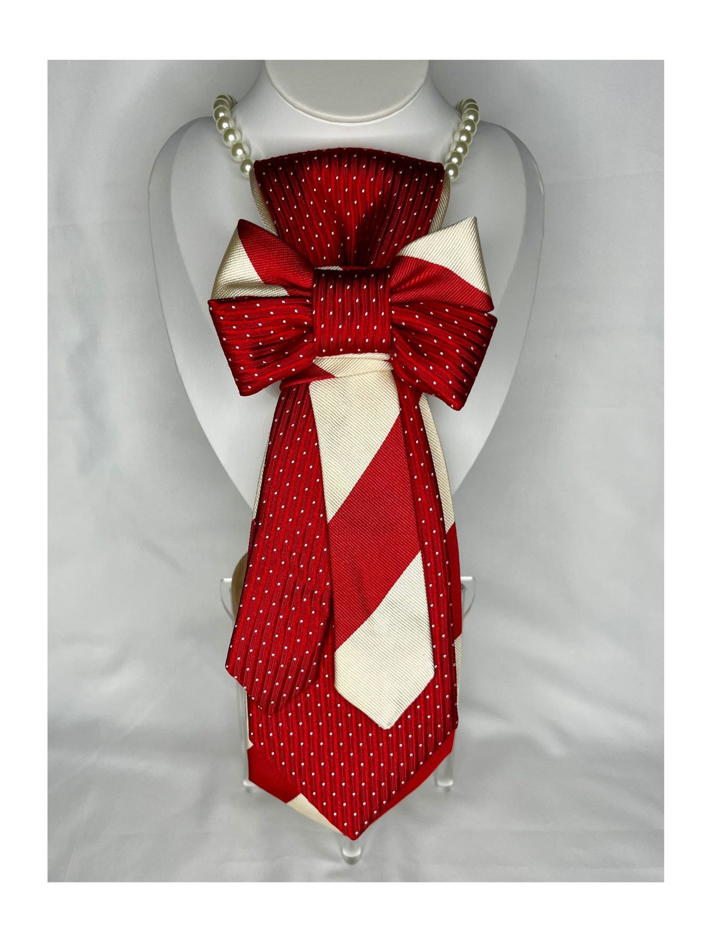 Röd handgjord julslipsrosett med vita detaljer fotograferad framifrån i helvy