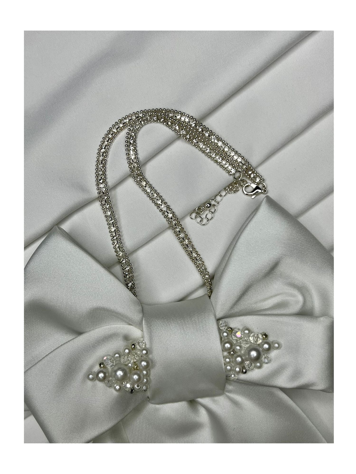 Närbild av halskedja för handgjord slipsrosett vit ton med pärldetaljer