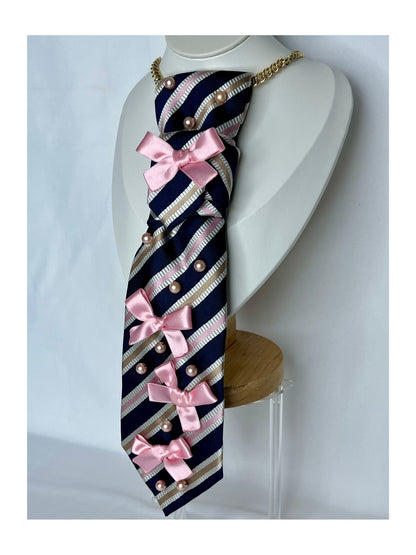 Närbild från sidan av slipsrosett i marinblå bas med diagonala ränder, rosa rosetter