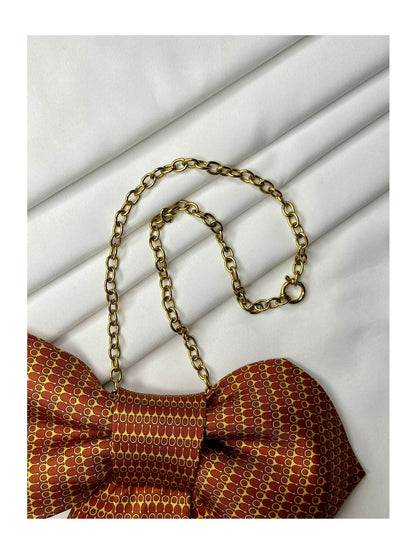 Närbild av halskedja för Slipsrosett i varm kopparton med ett finvävt mönster