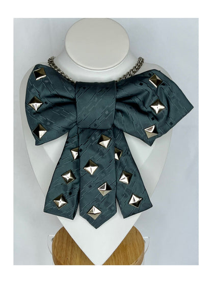 Bild framifrån av slipsrosett i petrolgrön ton med markerade nitar och dekorativ kedja