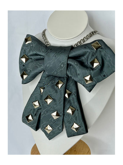 Närbild från sidan av slipsrosett i petrolgrön ton med markerade nitar och dekorativ kedja