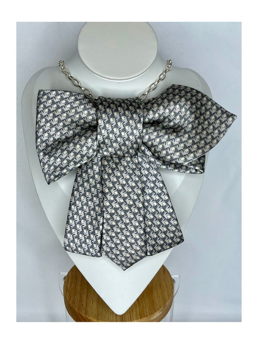 Bild framifrån av flugrosett i silvergrå ton med grafiskt mönster